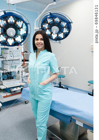 Smiling female surgeon poses at operating table Smiling female surgeon poses at operating table 69846131