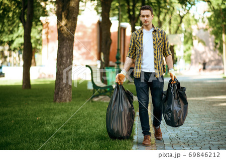 Man holds plastic trash bags in park, volunteering 69846212