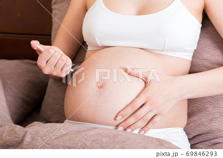 Pregnant woman with insulin syringe in home on bed. Pregnant diabetes concept 69846293