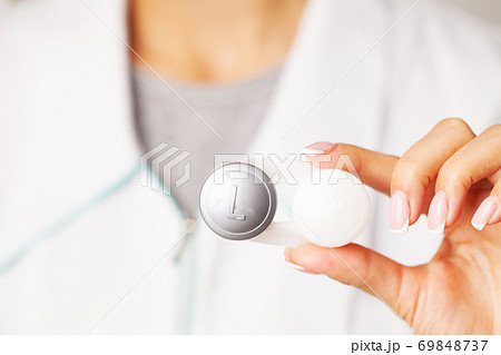 Woman holding plastic container with contact lenses Woman holding plastic container with contact lenses 69848737