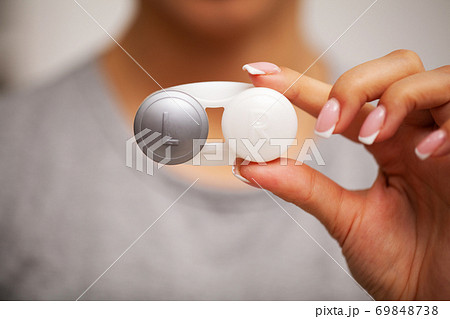 Woman holding plastic container with contact lenses Woman holding plastic container with contact lenses 69848738