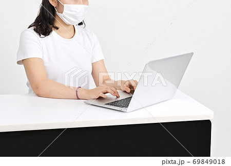 マスクをして仕事をする女性　女性とノートパソコン　デスクワークの女性　マスクで感染予防　イメージ素材 69849018