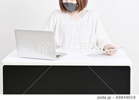 マスクをして仕事をする女性　女性とノートパソコンとタブレット　デスクワークの女性　マスクで感染予防　 69849019