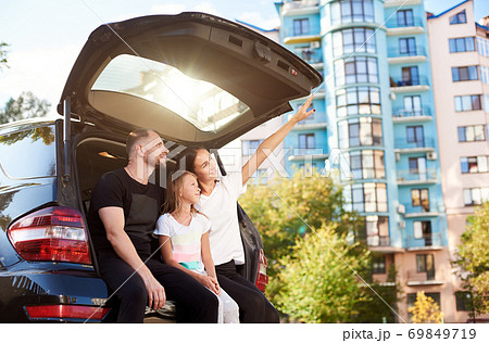 Family - father, mother, daughter are sitting in the car trunk. Family - father, mother, daughter are sitting in the car trunk. 69849719