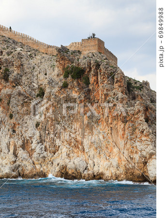 Alanya Castle.  The fortified walls of Alanya Castle in Southern Turkey as viewed from the Mediterranean Sea. The castle is located on a rocky peninsula and dates back to the 13th century. 69849988