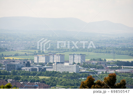 丘の上から見下ろすエジンバラ郊外に建てられたビル群と遠くにかすむ山々 69850547