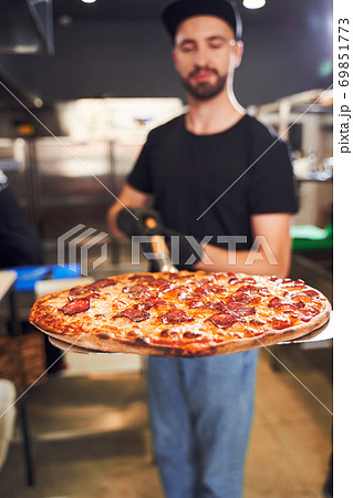 Pizzaiolo holding pizza on peel Pizzaiolo holding pizza on peel 69851773