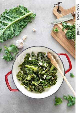 Sauteed kale with garlic in cast iron pan on kitchen table, healthy food concept, superfood Sauteed kale with garlic in cast iron pan on kitchen table, healthy food concept, superfood 69851955
