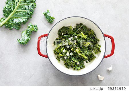 Sauteed kale with garlic in cast iron pan on kitchen table, healthy food concept, superfood Sauteed kale with garlic in cast iron pan on kitchen table, healthy food concept, superfood 69851959