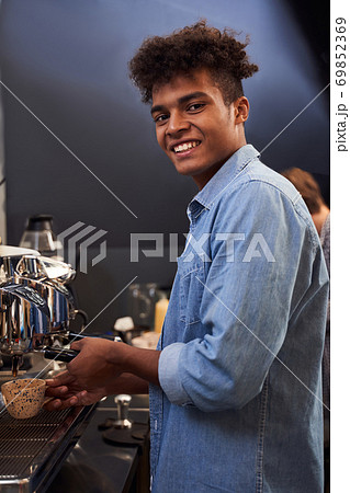 Barista brews coffee for his clients Barista brews coffee for his clients 69852369