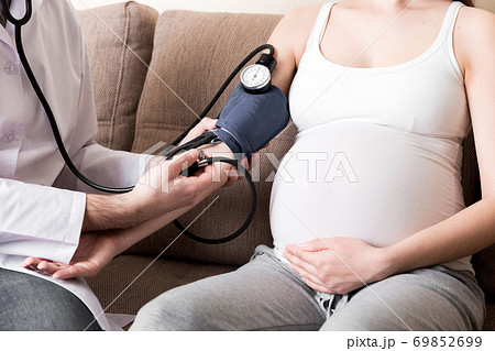 Young doctor is checking blood pressure of pregnant woman at home. High pressure problem during pregnancy concept 69852699