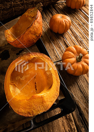 Baked and raw pumpkins on old wooden background 69852844