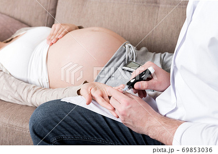 Young doctor is checking blood sugar glucose of pregnant woman at home 69853036