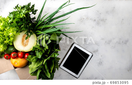 Box full of Different organic vegetables and greens and tablet computer. Top view. Box full of Different organic vegetables and greens and tablet computer. Top view. 69853095