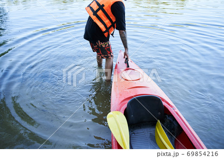 Man in safe jacket pulling canoe Man in safe jacket pulling canoe 69854216