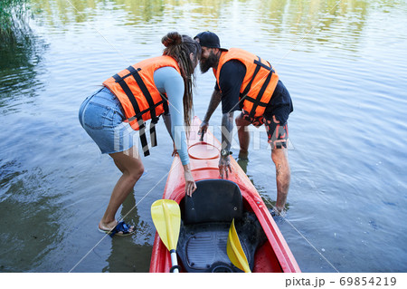 Man and woman in safe jackets pulling canoe Man and woman in safe jackets pulling canoe 69854219