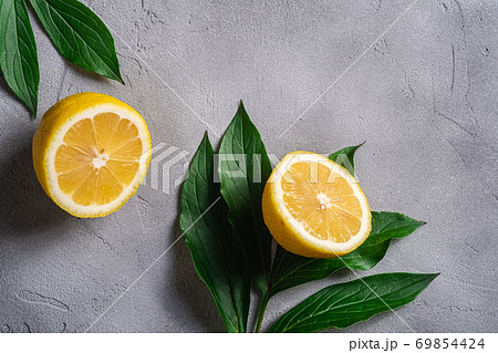 Two lemon slices, tropical citrus fruits with green leaves on grey concrete background, top view 69854424