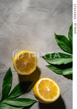 Two lemon slices, tropical citrus fruits with green leaves on grey concrete background, top view copy space 69854425