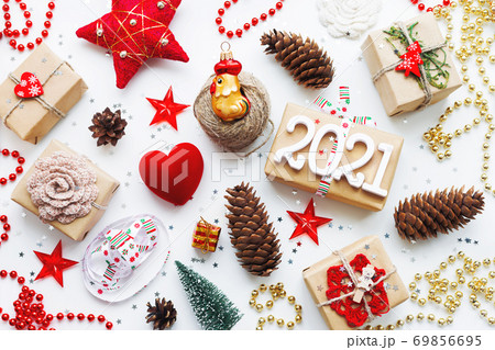 Christmas presents with decorations. New Year 2021 gifts in craft paper, pine cones, red hearts and confetti. Flay lay, top view background. 69856695