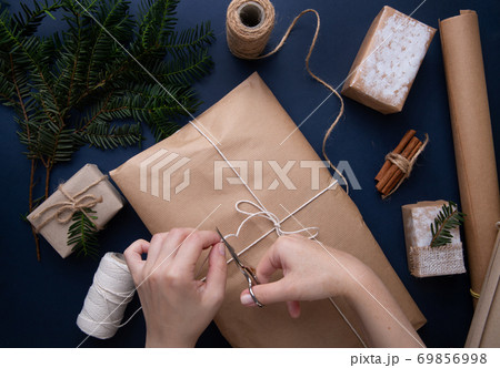 Hands wrapping a Christmas present on a blue table 69856998