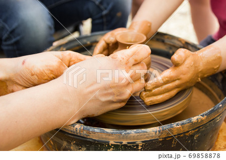 A close up view on ceramic production process on potter's wheel with children. Clay crafts with kids concept 69858878