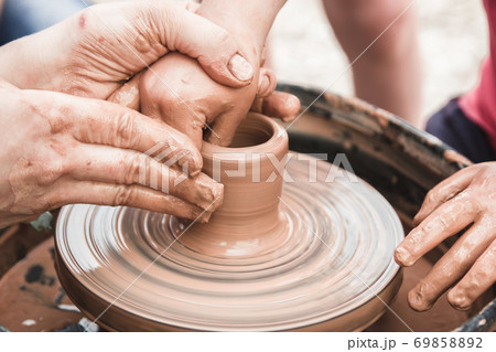A close up view on ceramic production process on potter's wheel with children. Clay crafts with kids concept A close up view on ceramic production process on potter's wheel with children. Clay crafts with kids concept 69858892