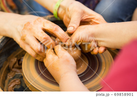 A close up view on ceramic production process on potter's wheel with children. Clay crafts with kids concept 69858901