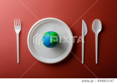 Serving table with Earth planet, plastic plate, spoon, fork and knife. Ecology Concept for Earth Hour, Earth Day, Ocean Day and other ECO dates. Serving table with Earth planet, plastic plate, spoon, fork and knife. Ecology Concept for Earth Hour, Earth Day, Ocean Day and other ECO dates. 69863147