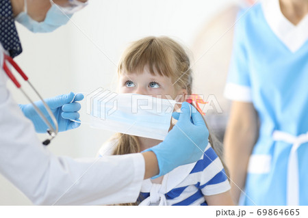 Little girl is put on protective medical mask in doctor's office. Little girl is put on protective medical mask in doctor's office. 69864665