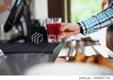 Woman's hand holds glass in cafe with red liquid similar to fruit drink or jelly 69864728