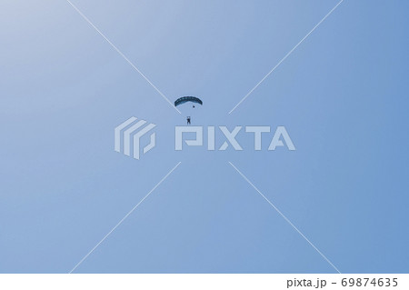 Tandem parachute jump. Silhouette of skydiver flying in blue clear sky. Tandem parachute jump. Silhouette of skydiver flying in blue clear sky. 69874635