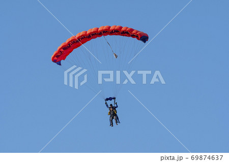 Tandem parachute jump. Silhouette of skydiver flying in blue clear sky. Tandem parachute jump. Silhouette of skydiver flying in blue clear sky. 69874637