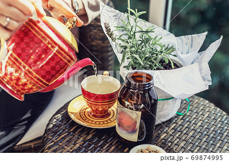 Woman's hand pouring tea from teapot to cup Woman's hand pouring tea from teapot to cup 69874995