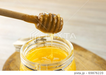 Honey dripping from a wooden dipper in jar on old Honey dripping from a wooden dipper in jar on old 69876220