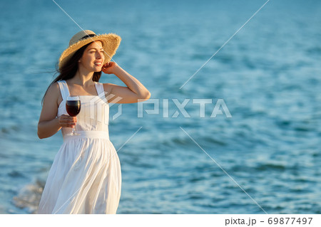woman holding glass of wine by the sea woman holding glass of wine by the sea 69877497
