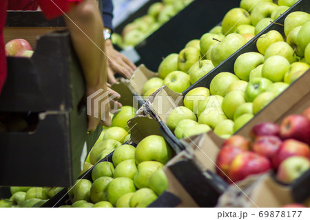 Young man seller lays out fresh fruits of the box on the grocery store 69878177