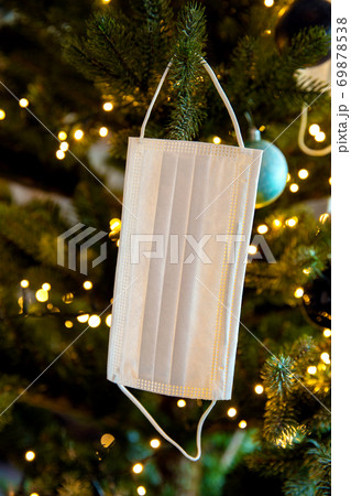 Christmas tree with Coronavirus face mask hanging in tree, decorated with Covid-19 safety mask and Christmas balls for bright Christmas 69878538