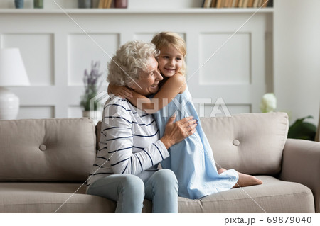 Adorable preschool girl holding arms around neck of mature grandmother 69879040