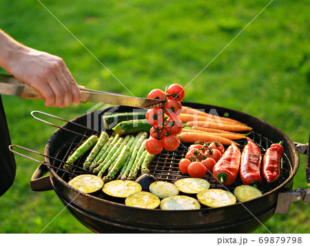 Scene of a man grilling vegetables outdoor. Scene of a man grilling vegetables outdoor. 69879798