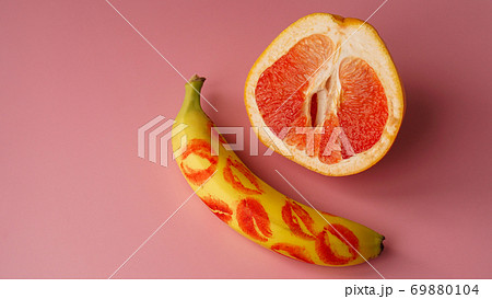 Banana with traces of red lipstick and grapefruit on pink background Banana with traces of red lipstick and grapefruit on pink background 69880104
