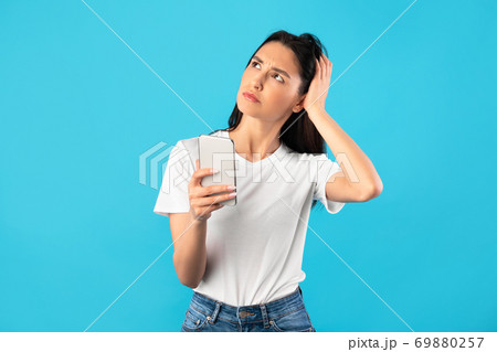 Confused upset young woman holding mobile phone 69880257