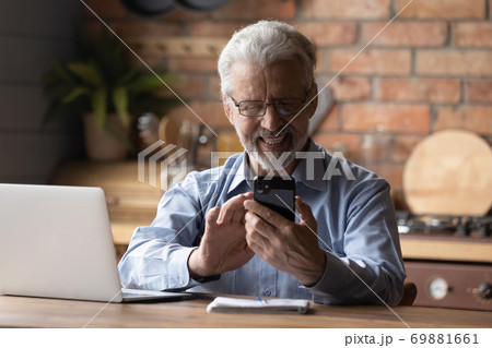 Smiling old man use smartphone work on laptop 69881661