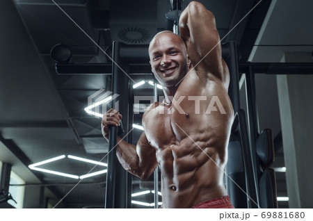 Bodybuilder strong man pumping up abs muscles 69881680
