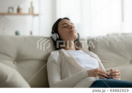 Millennial girl in headphones relaxing on sofa at home Millennial girl in headphones relaxing on sofa at home 69882929