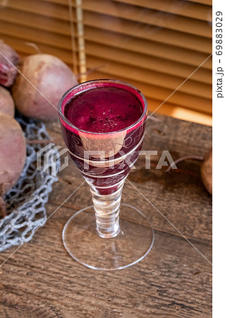 Red beet juice in a glass on a wooden table 69883029