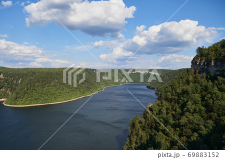 Blue water in a forest lake with pine trees. Blue water in a forest lake with pine trees. 69883152