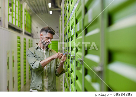 Man Opening Lock on Storage Unit Man Opening Lock on Storage Unit 69884898