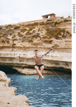 A man swimming in a body of water. Jumping from rock to the water with salto A man swimming in a body of water. Jumping from rock to the water with salto 69885802