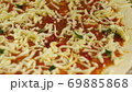 Cooking pizza. Chef put cheese and basil on the base of the pizza greased with tomato paste. A man 69885868