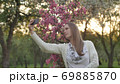 Girl makes selfie in the garden. An attractive red-haired woman smiles making selfi using a mobile 69885870